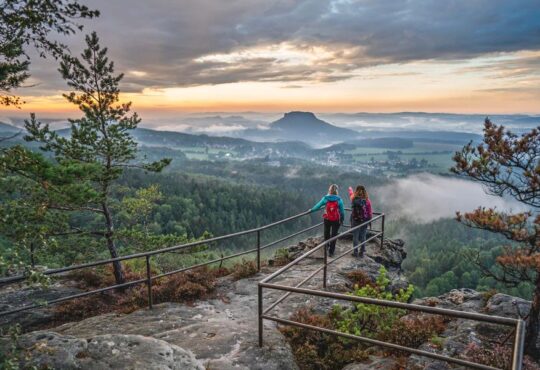 Zwei Wanderinnen genießen den Sonnenuntergang auf dem Papstein. Foto: TVSSW/Philipp Zieger